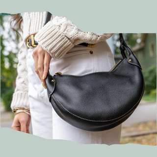 woman wearing white sweater and white pants holding black purse